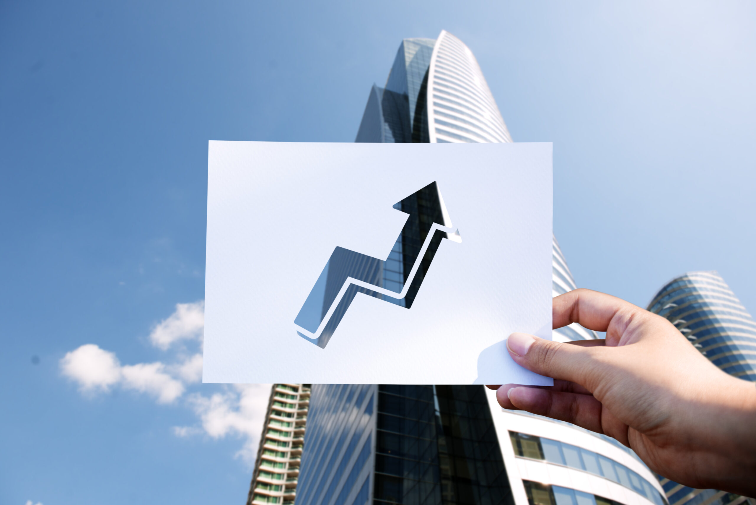 Rectangular piece of paper held in the air with an arrow pointing outwards depicting growth.