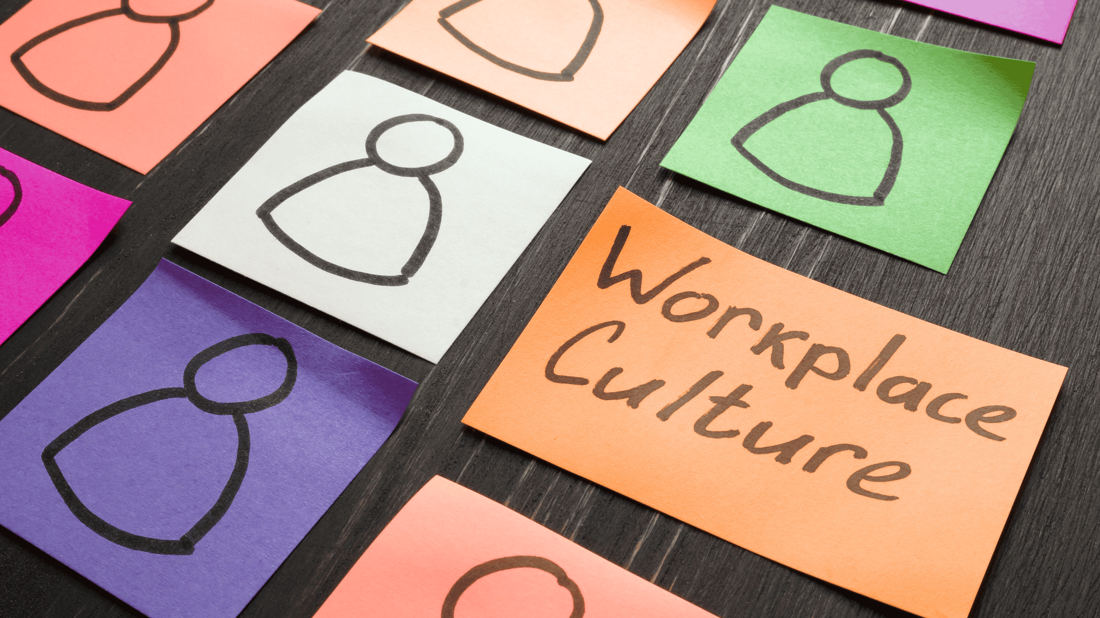 Coloured sticky notes arranged on a desk, each showing a simple outline of a person. One orange note in the centre reads “Workplace Culture,” symbolising an inclusive workplace culture that values diversity and inclusion.